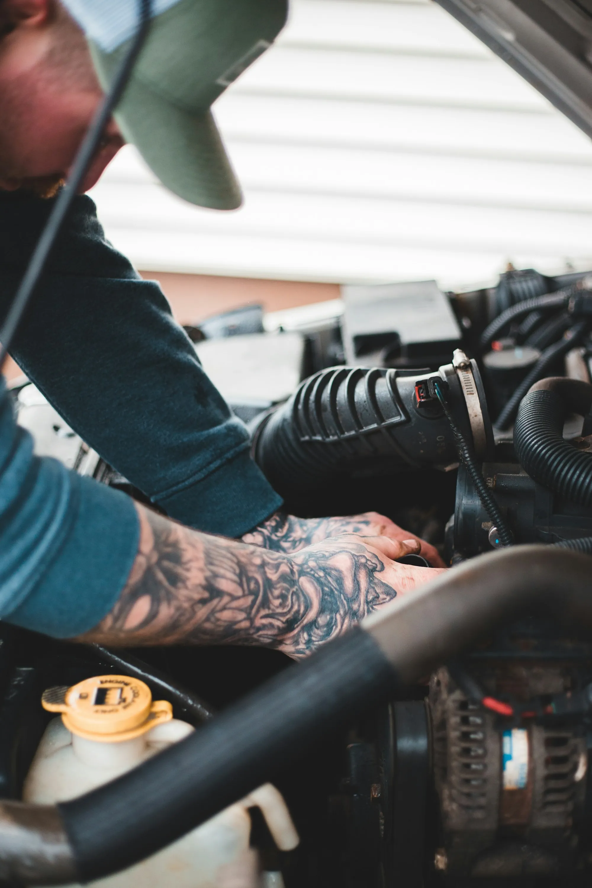 Mechanic with tattooed arms working on an engine