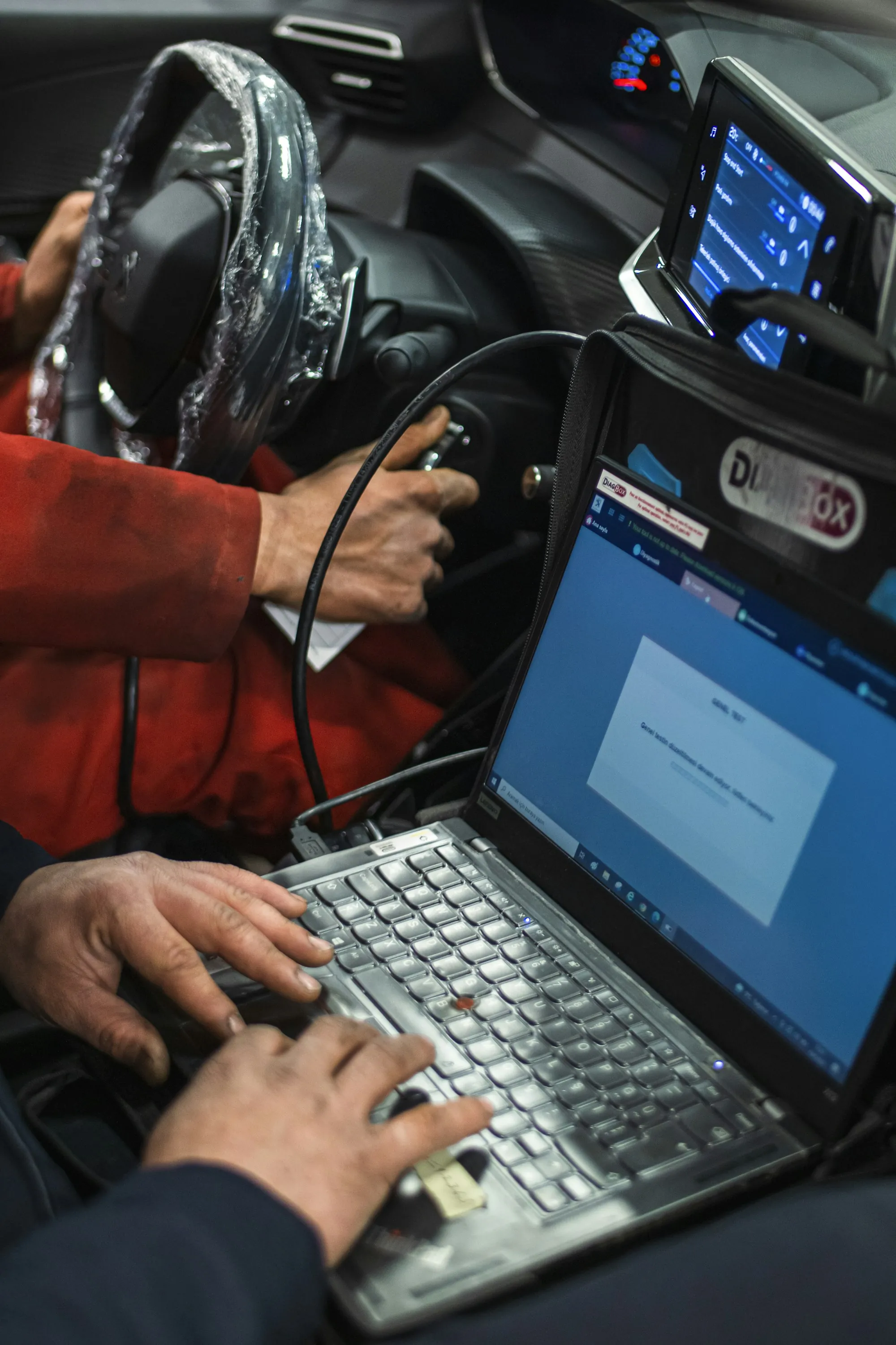 Technician using a laptop inside a car to read fault data