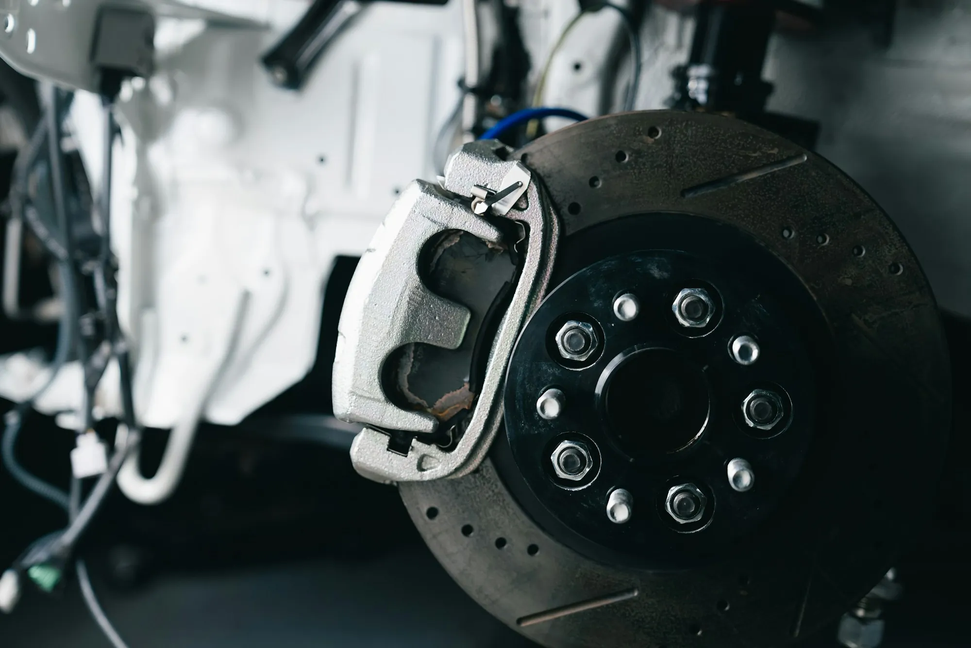 Drilled brake rotor and caliper on a vehicle with the wheel off