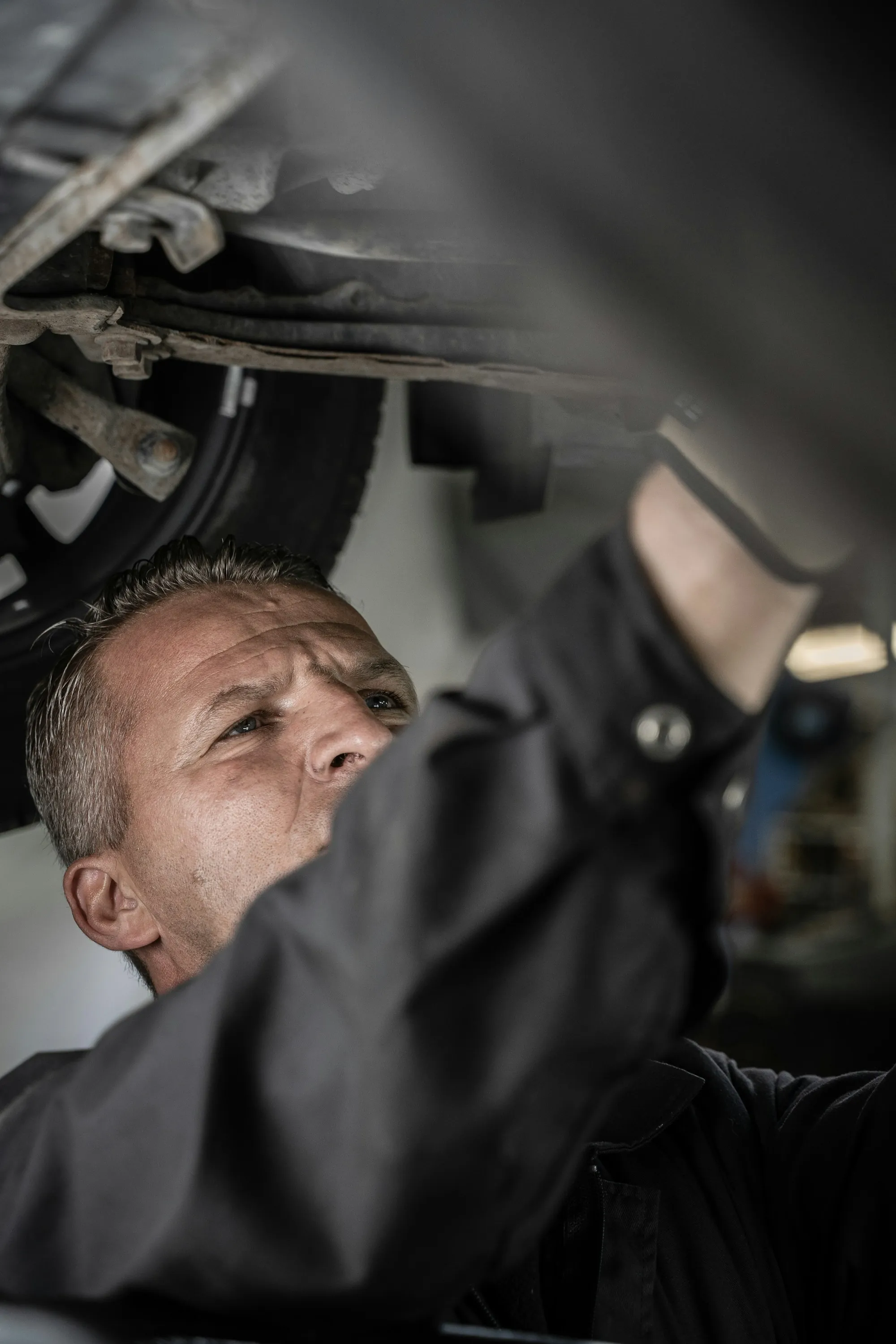 Mechanic working underneath a vehicle raised on a lift